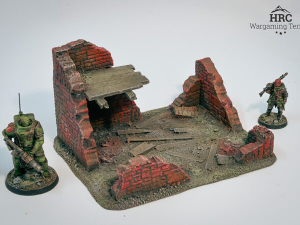 Detailed charred beams and rubble on a ruined brick shelter, hand-painted wargaming scenery.