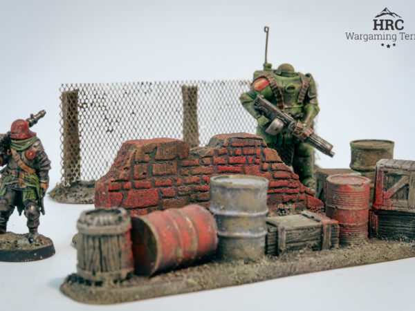 Detailed rusted barrels and splintered crates on a grimdark barricade, hand-painted wargaming scenery.
