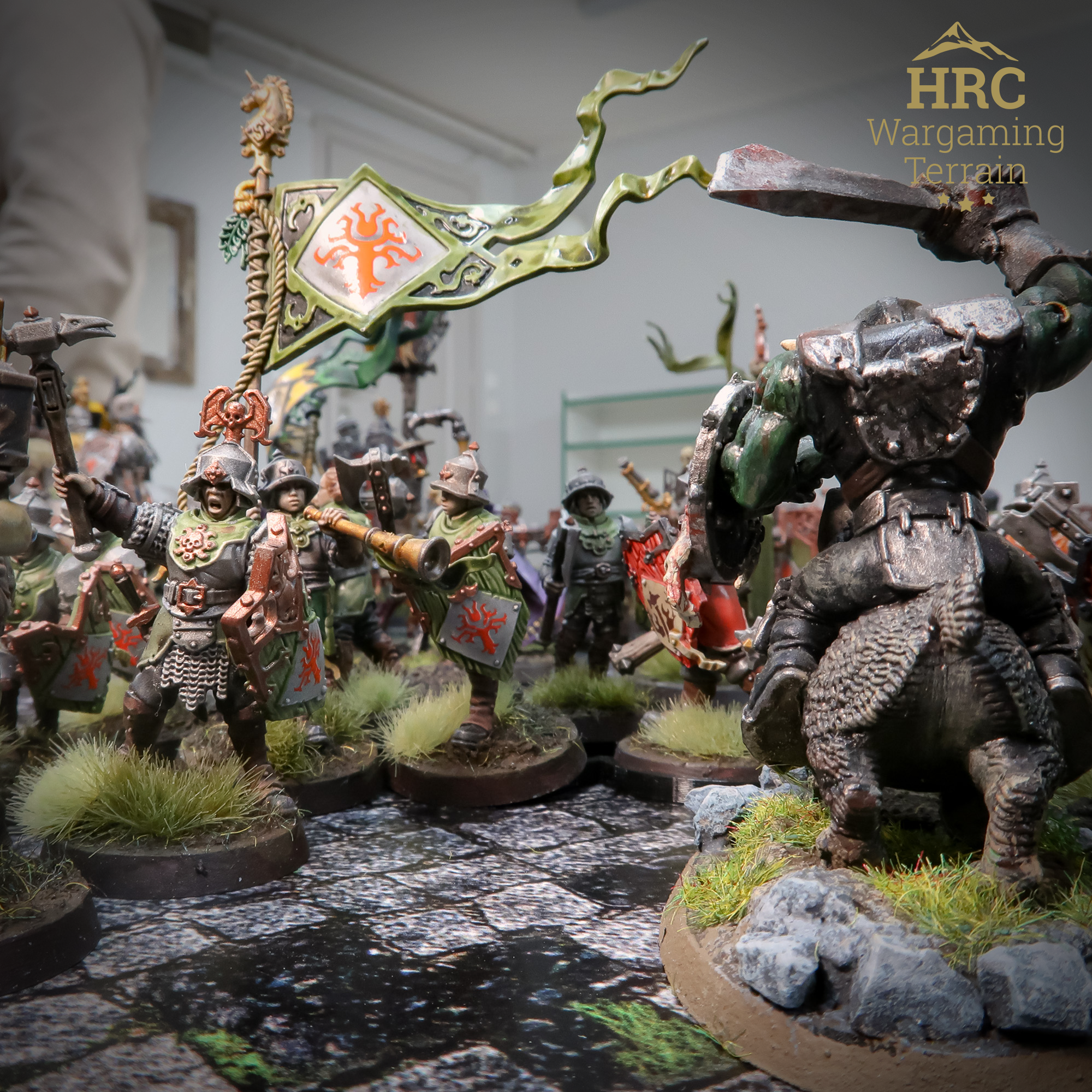 Human warriors battling a giant orc over stone walls and fences in Age of Sigmar wargaming terrain setup